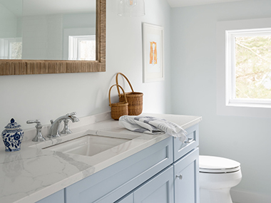 Cohasset bathroom with light blue vanity and white countertops with gray veining. Design by JP Hoffman Design Build