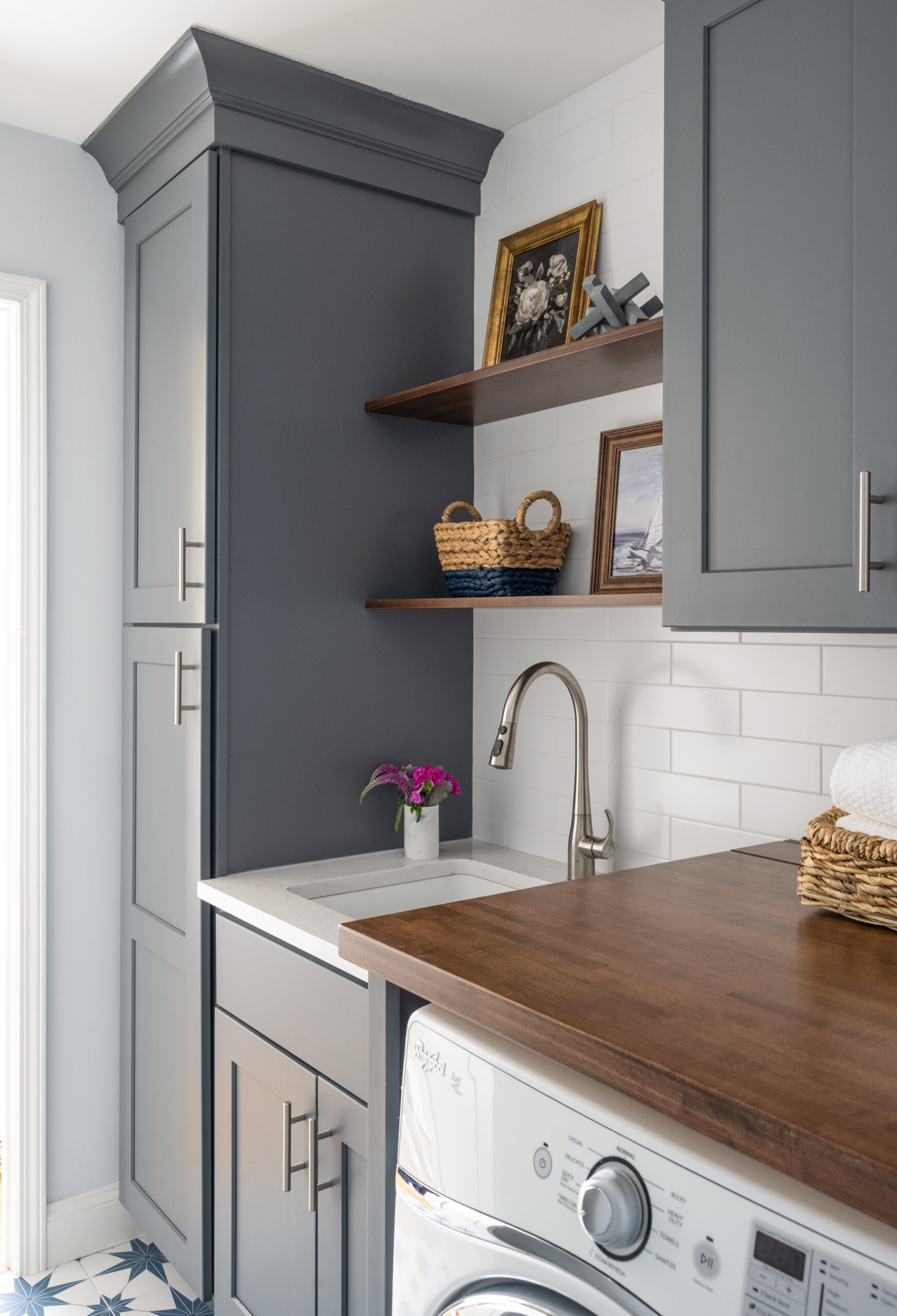 Needham laundry room with deep bluish gray cabinets, laundry room sink and walnut countertop. Design by JP Hoffman Design Build